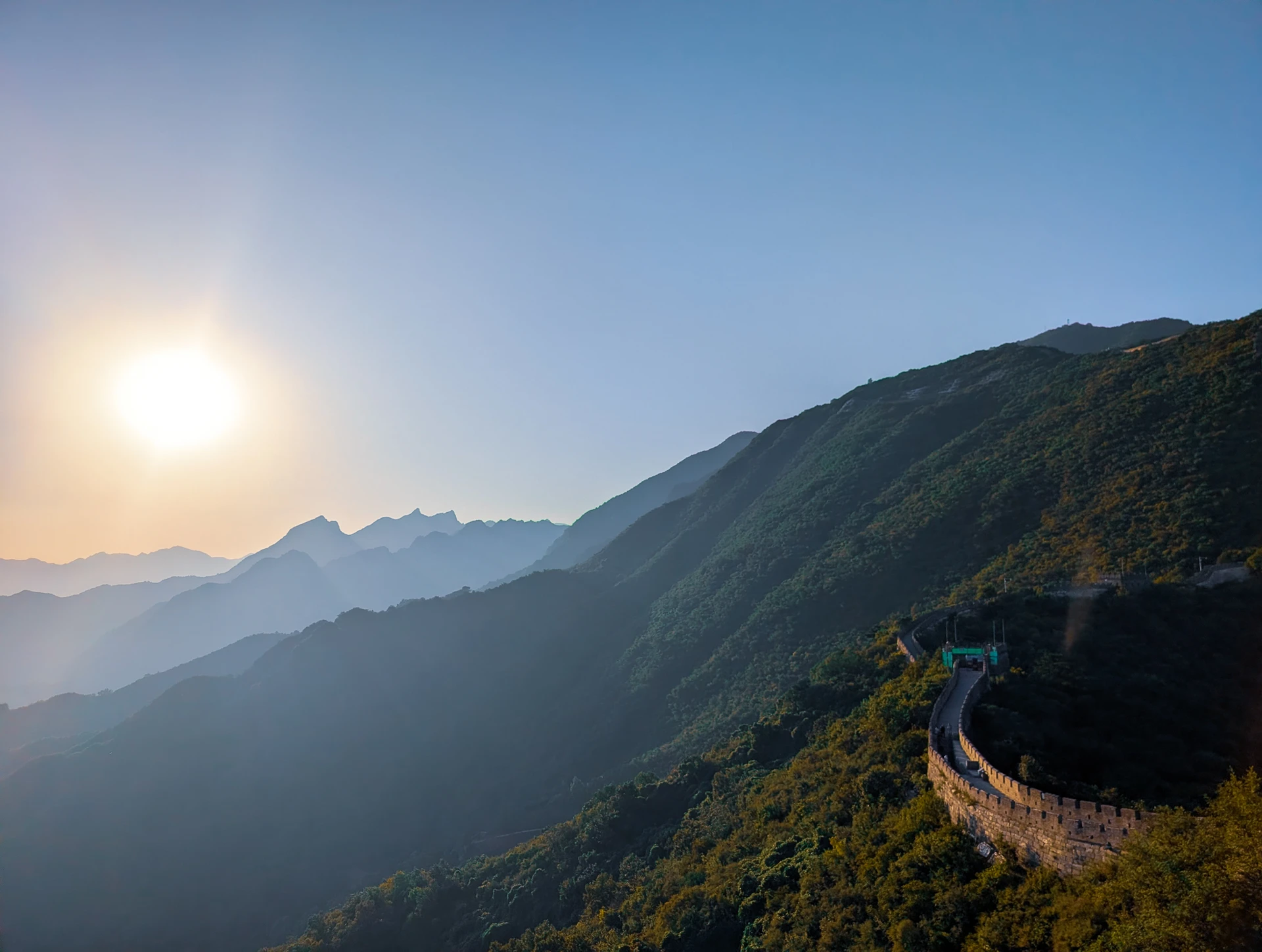 The Great Wall winding across green mountain ridges in the late afternoon sun