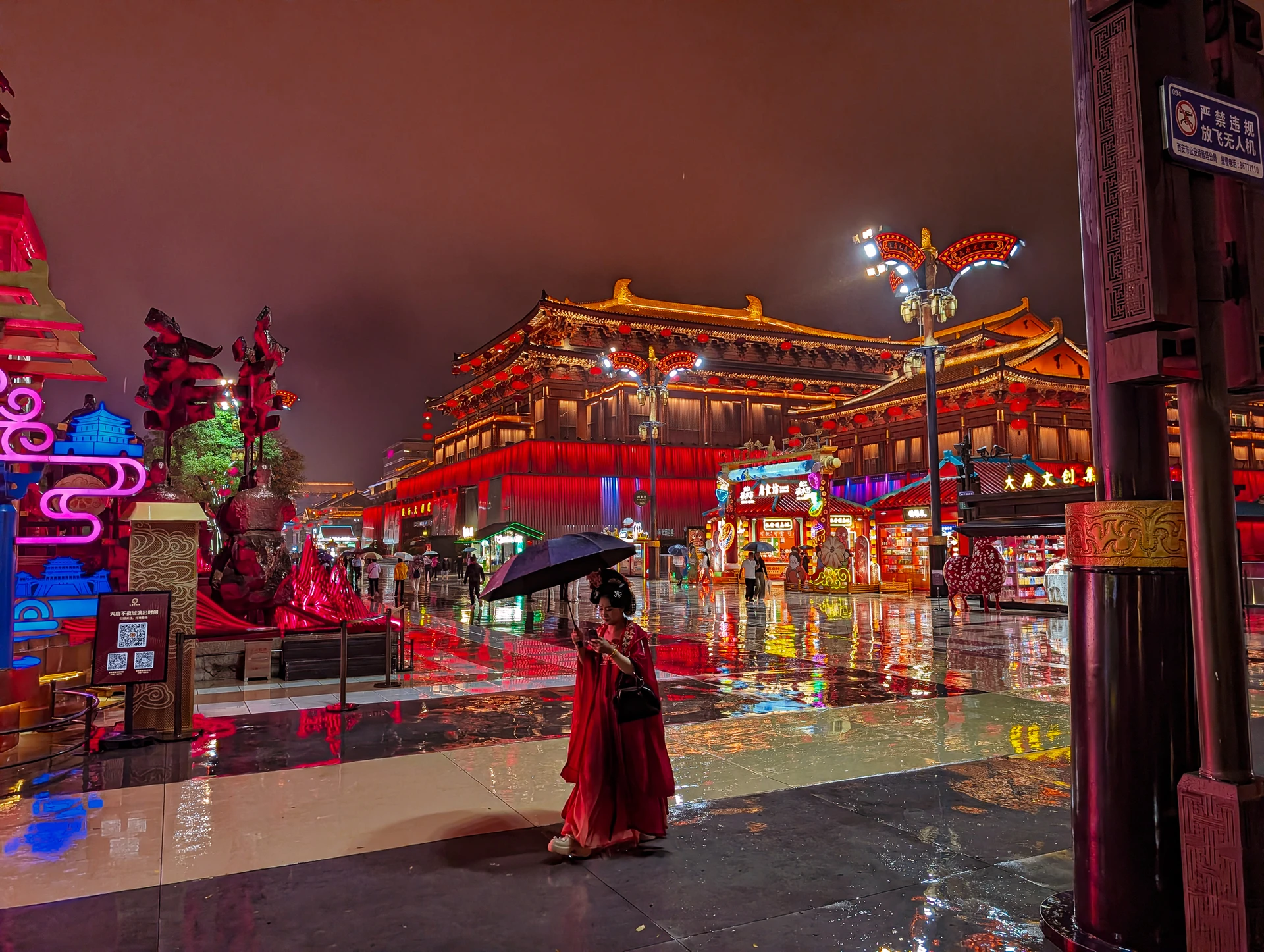 An illuminated traditional building reflected in a rain-soaked square at night